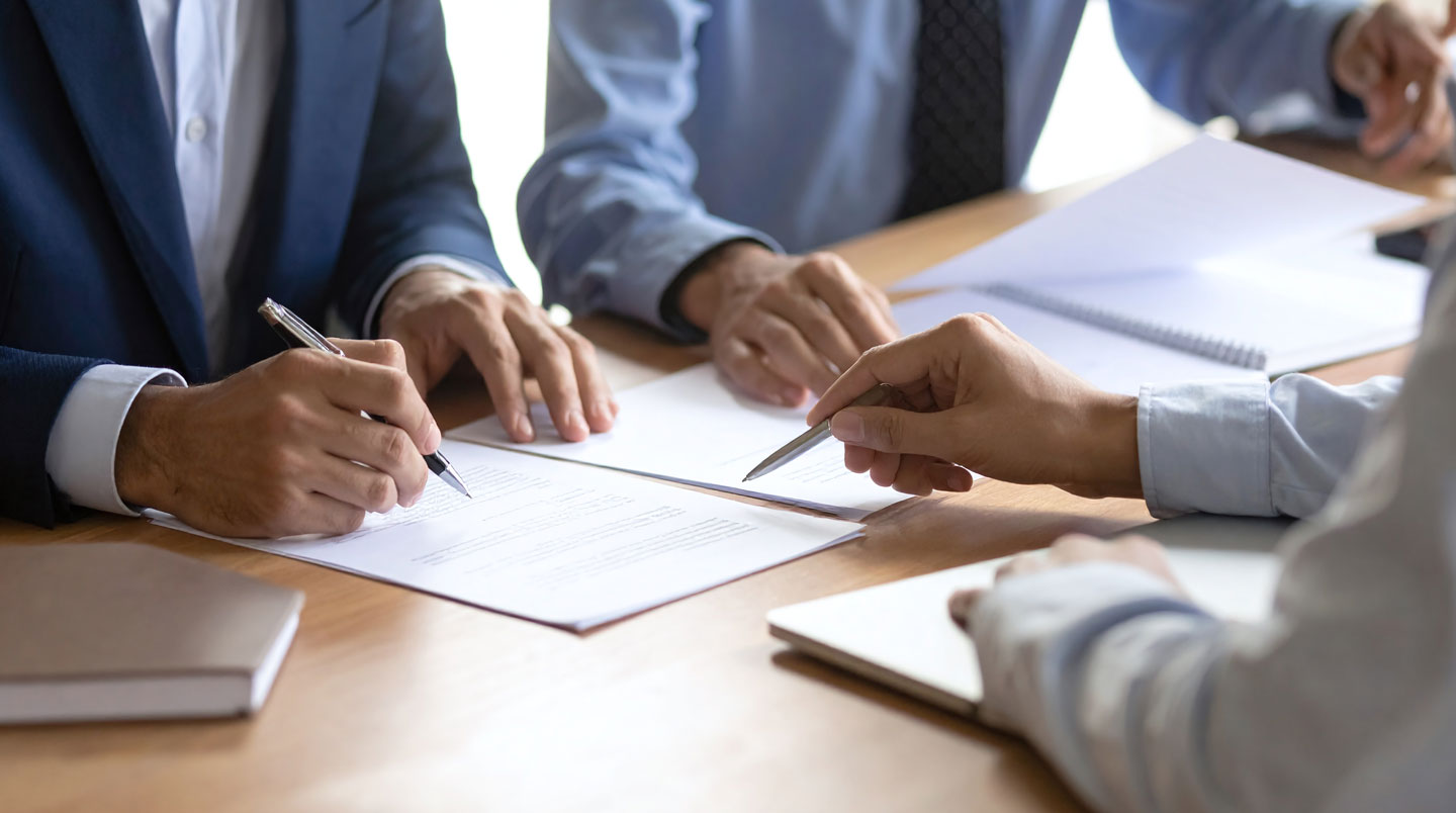Loupe vintage en laiton posée sur un contrat d'assurance ouvert avec passages surlignés en jaune symbolisant l'audit des clauses et exclusions